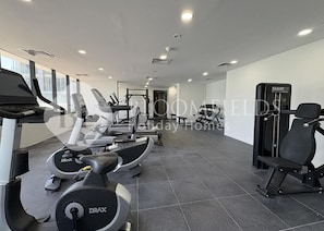 A gym with treadmills, elliptical machines, and weightlifting equipment. - Bloomfields 1BR in Al Maryah Vista  (Abu Dhabi)