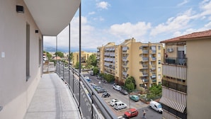 Un balcone con vista su una zona residenziale, con edifici a più piani e auto parcheggiate.