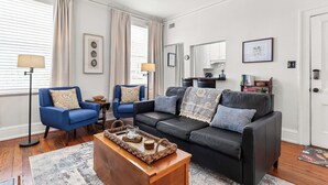 A living room with two sofas, a coffee table, and a dining area with a table and chairs. - Walk to Forsyth Park, Dining & Savannah Squares by Lucky Savannah (Savannah)