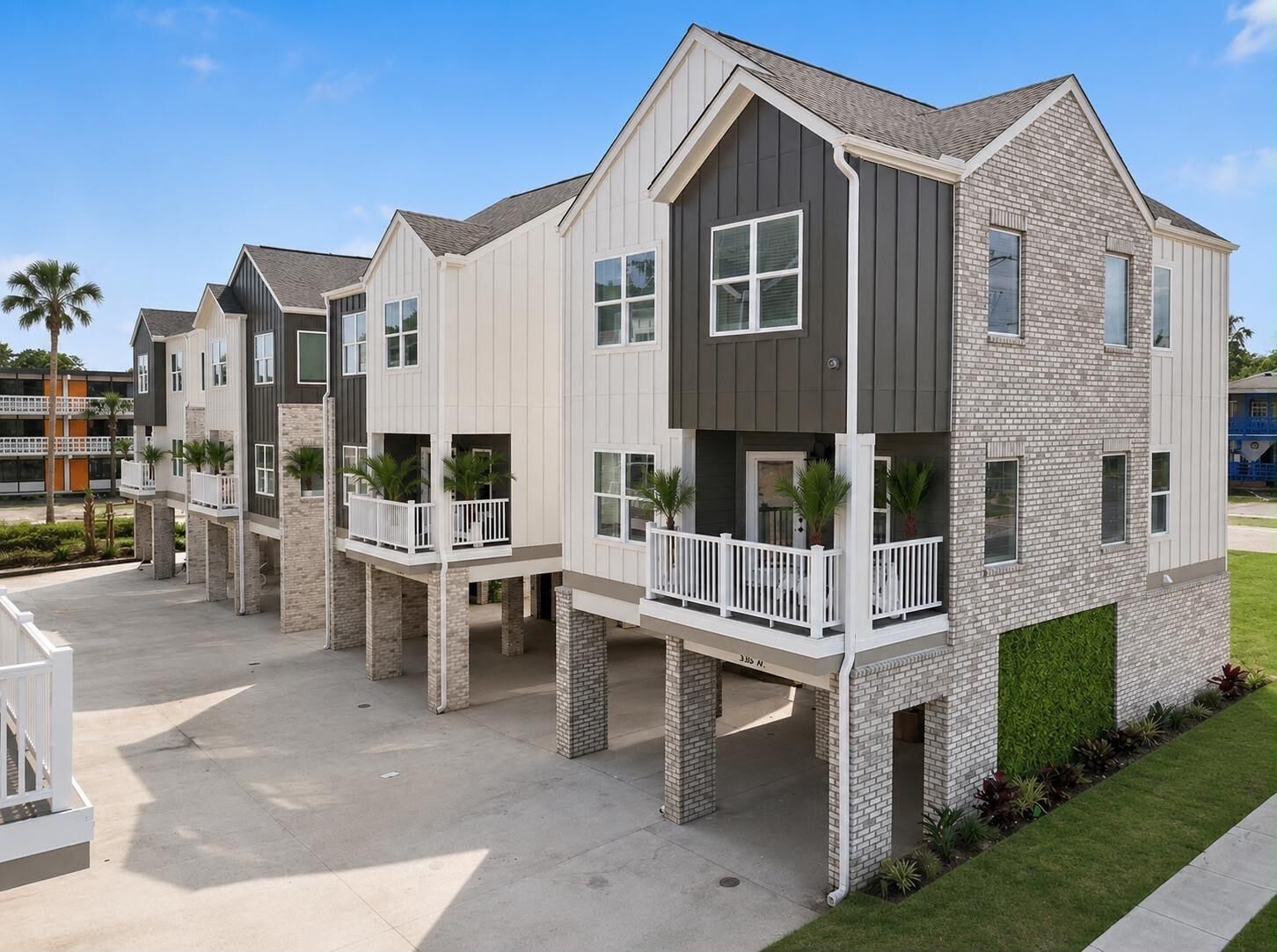 A modern multi-story residential building with a flat roof, large windows, and a balcony on each floor.