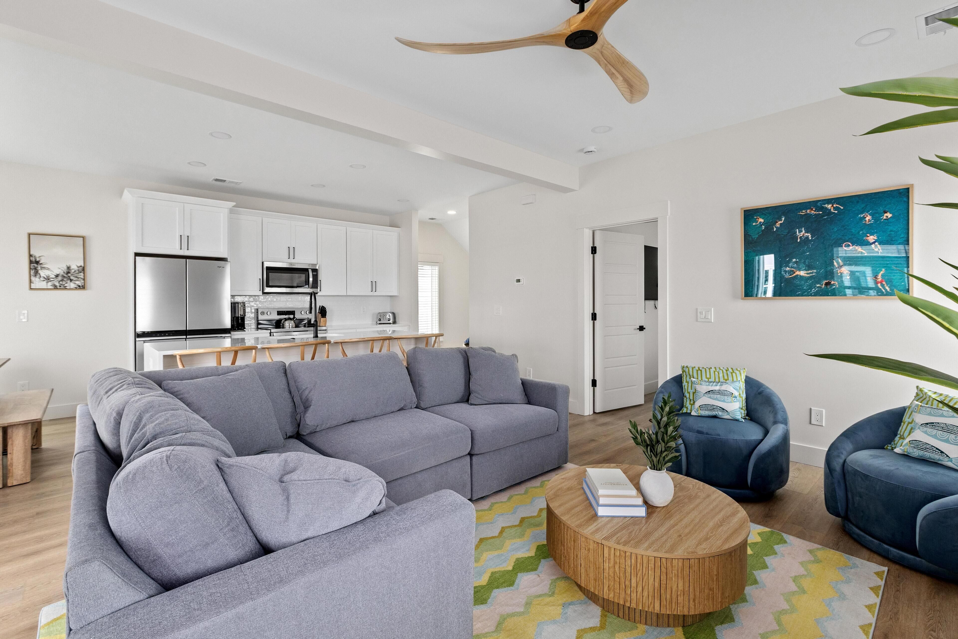 A modern living room with a sectional sofa, a round coffee table, and a ceiling fan.