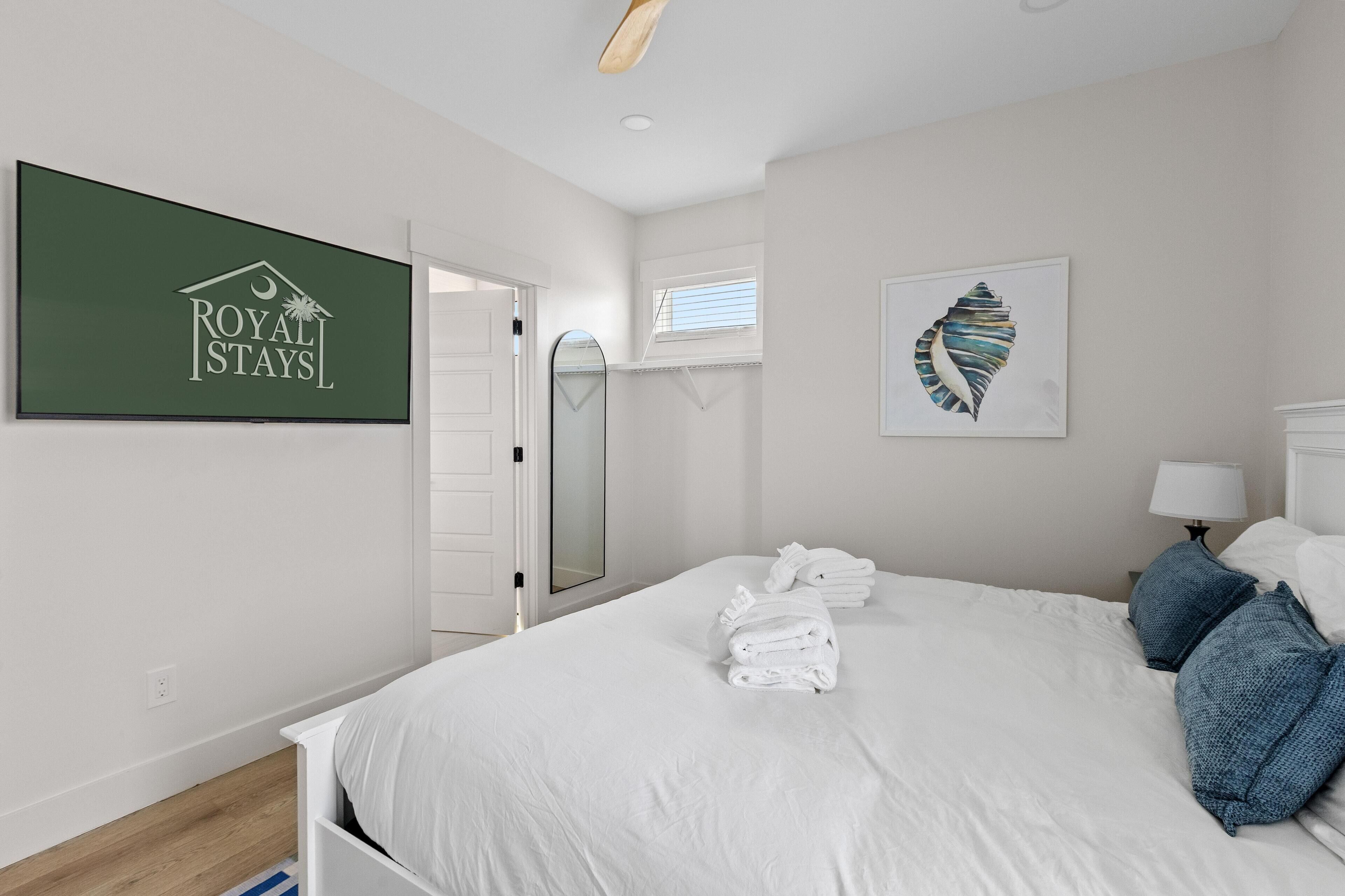 A hotel room with a bed, a mirror, a framed artwork, and a 'ROYAL STAYS' sign.