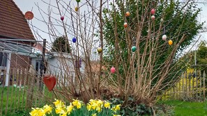 Ein Garten mit einem Baum, geschmückt mit bunten Verzierungen und Maiglöckchen.