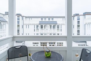 A balcony with two chairs, a round table, and a view of a white building with balconies. - Gemutliche Ferienwohnung im Ostseebad Sellin mit Balkon (Sellin)