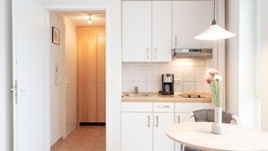 A modern kitchen with white cabinets, a wooden countertop, a coffee maker, and a vase with flowers on the table. - Gemutliche Ferienwohnung im Ostseebad Sellin mit Balkon (Sellin)