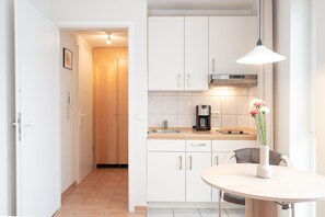 A modern kitchen with white cabinets, a wooden countertop, a coffee maker, and a vase with flowers on the table. - Gemutliche Ferienwohnung im Ostseebad Sellin mit Balkon (Sellin)