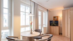 A modern room with a dining table, chairs, a vase with flowers, a television, and a cabinet. - Gemutliche Ferienwohnung im Ostseebad Sellin mit Balkon (Sellin)
