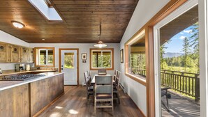 A kitchen with wooden cabinets, a central island, and a dining area with chairs and a table. - Private Sampson Lake frontage home - Bordering Whitefish City Limits (Whitefish)