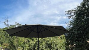 Une terrasse en bois avec une table et des chaises, un parasol et une clôture.