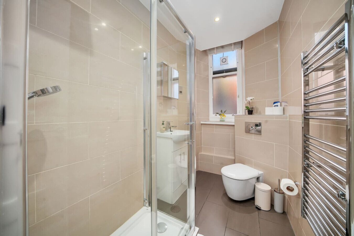 Ein modernes Badezimmer mit Duschkabine aus Glas, Toilette und integriertem Waschtisch.