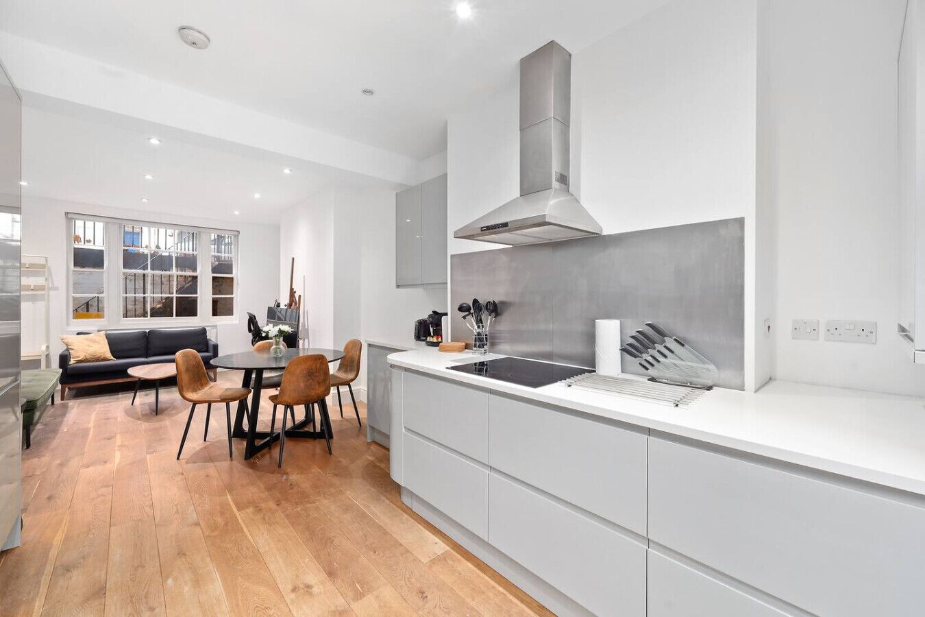 Une cuisine moderne dotée d’un îlot central, de meubles blancs et d’une hotte de cuisinière en acier inoxydable.