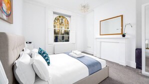 Une chambre à coucher avec un lit, une fenêtre, un radiateur, un miroir et une plante.