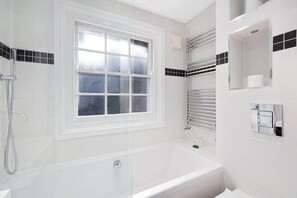 Ein modernes Badezimmer mit Badewanne, Fenster, Handtuchhalter und Toilettenpapierhalter.