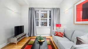 Un salon moderne avec un téléviseur, un canapé et une fenêtre avec des rideaux.