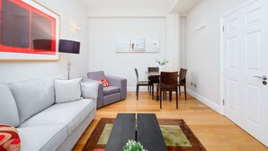 Un salon moderne avec un canapé gris, une table à manger avec des chaises, une table basse et une porte.
