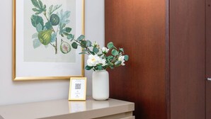 Une illustration botanique encadrée, un vase blanc rempli de fleurs et une pancarte d’accueil encadrée posée sur un comptoir.