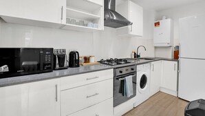 Eine moderne Küche mit Mikrowelle, Kaffeemaschine, Gasherd, Backofen und integriertem Waschmaschine.