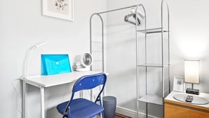 A compact room with a desk, chair, standing fan, and a small cabinet with a lamp. - Cosy Clapham Retreat - 2 Min Walk To Tube (Greater London)