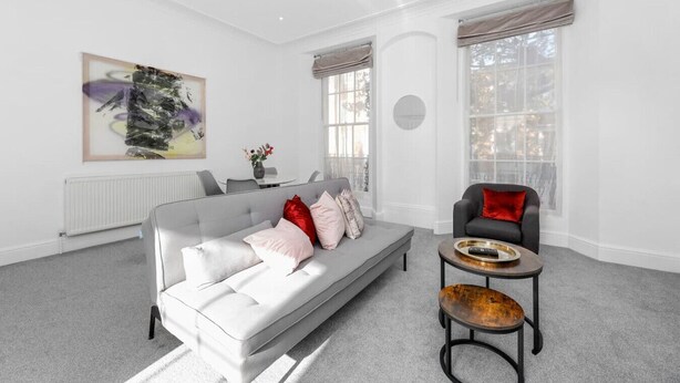 A modern living room with a grey sofa, a red chair, and a small table. - Chic 1BR Flat Walk to King’s Cross & St Pancras (Greater London)