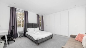 A bedroom with a bed, a desk, a chair, a wardrobe, and a sofa. - Chic 1BR Flat Walk to King’s Cross & St Pancras (Greater London)