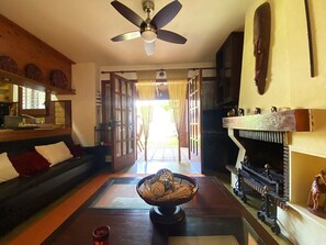 A living room with a sofa, a coffee table with a decorative bowl, a fireplace, and a ceiling fan. - Cozy townhouse with pool - 4 guests (Torredembarra)