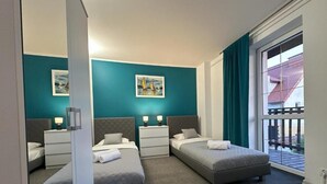Habitación de hotel con dos camas, un ventanal amplio y obras de arte en las paredes.