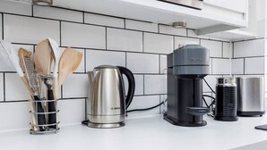 Una cocina con un hervidor Bosch, una cafetera Nespresso y un molinillo de café.