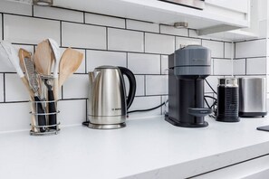 Eine Küche mit einem Wasserkocher von Bosch, einer Nespresso-Kaffeemaschine und einer Kaffeemühle.