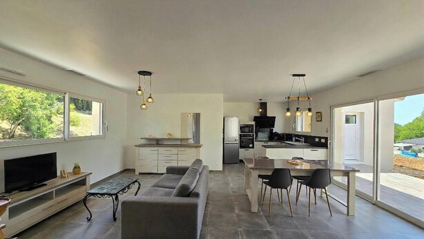 Una cocina moderna con comedor, sofá y televisor.