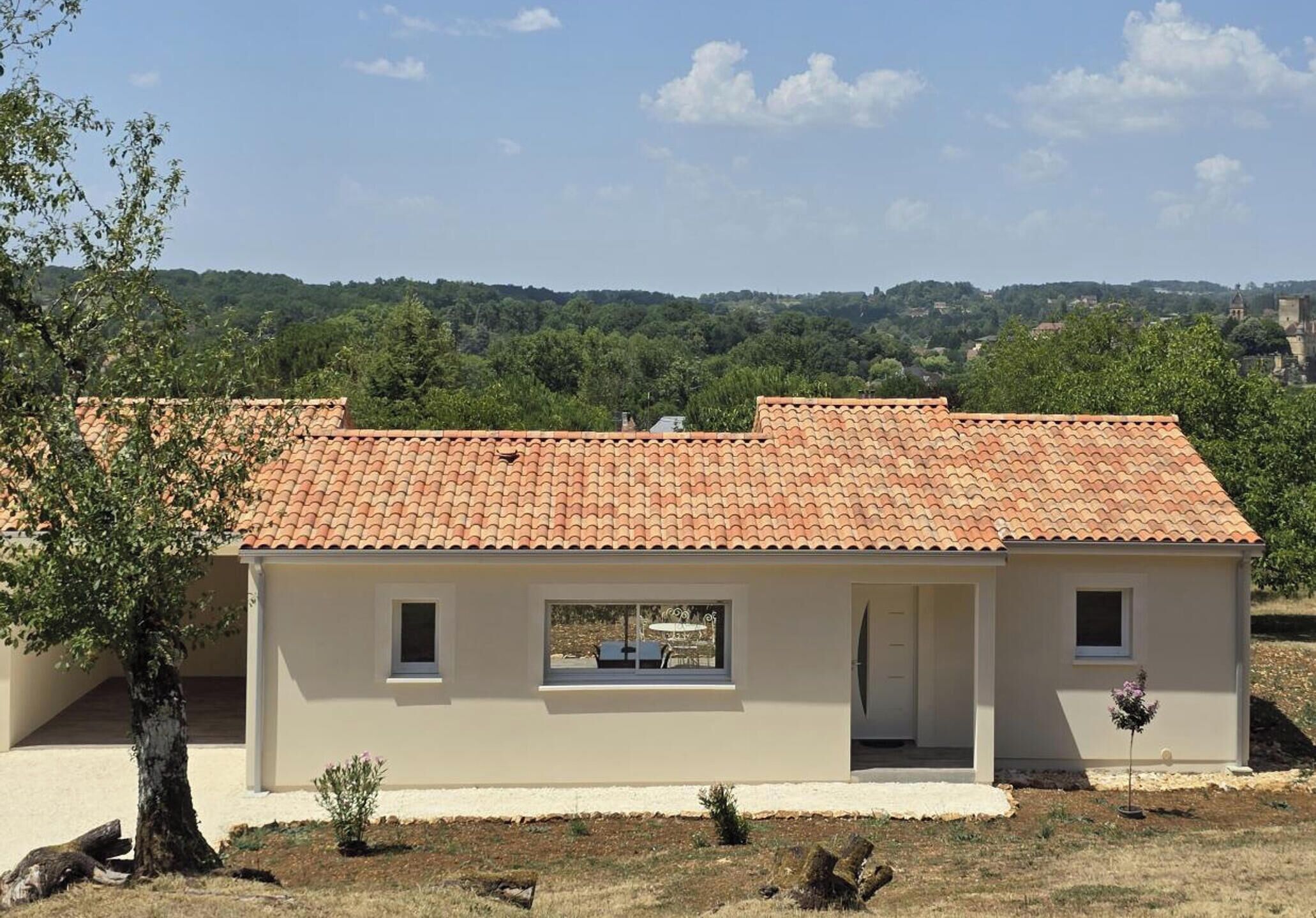 A single-story building with a tiled roof, a small porch, and a view of a hilly landscape.