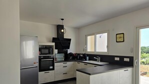Cocina moderna con refrigerador, horno, microondas y campana extractora negra.