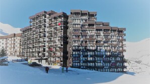 Un hotel a più piani con balconi e una pista da sci sullo sfondo.