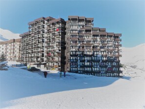 A multi-story hotel with balconies and a ski slope in the background. - Cozy studio, lake view - 4 guests (Tignes)