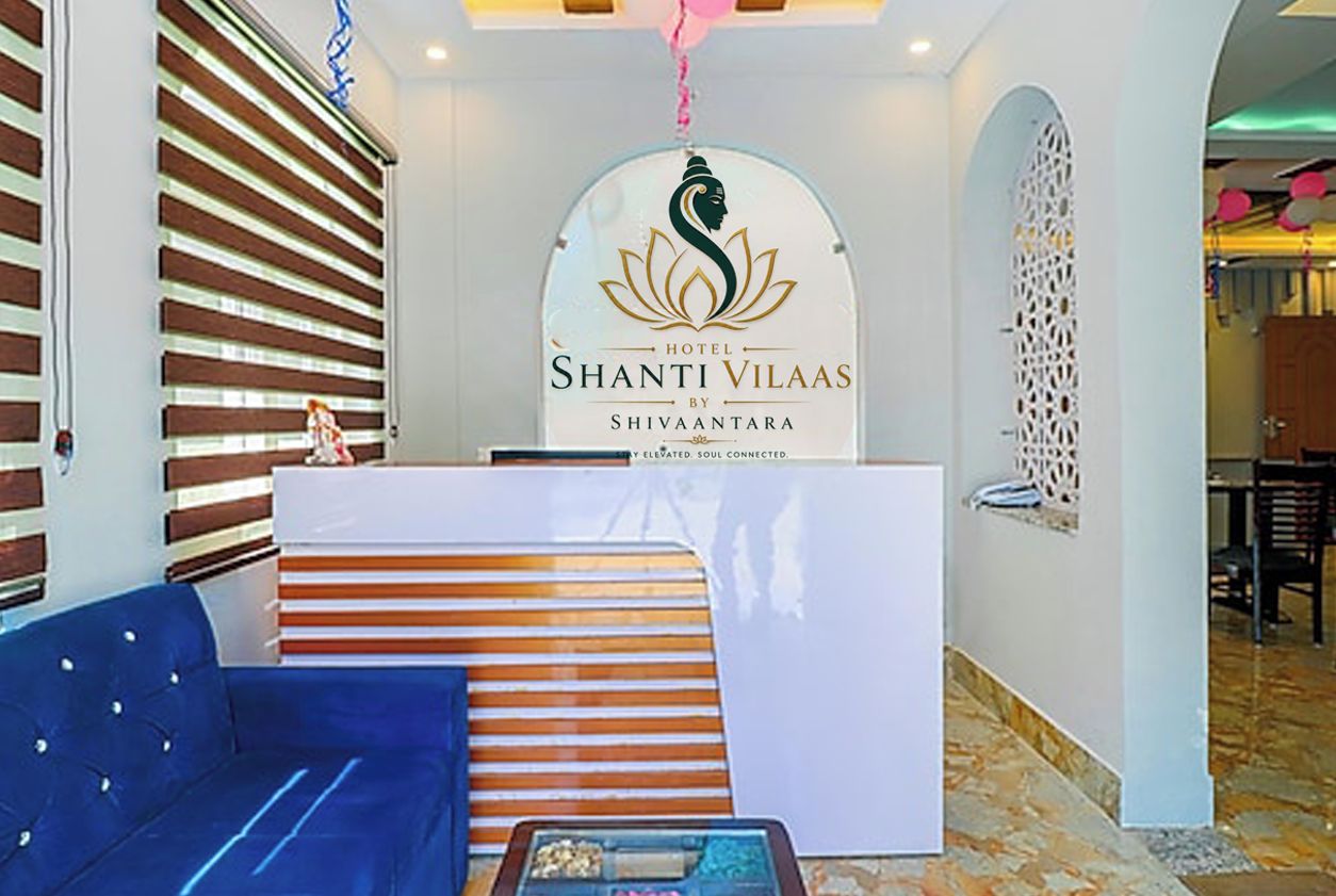 Un área de recepción con mostrador, un sofá azul y una pared decorativa con diseño de loto.