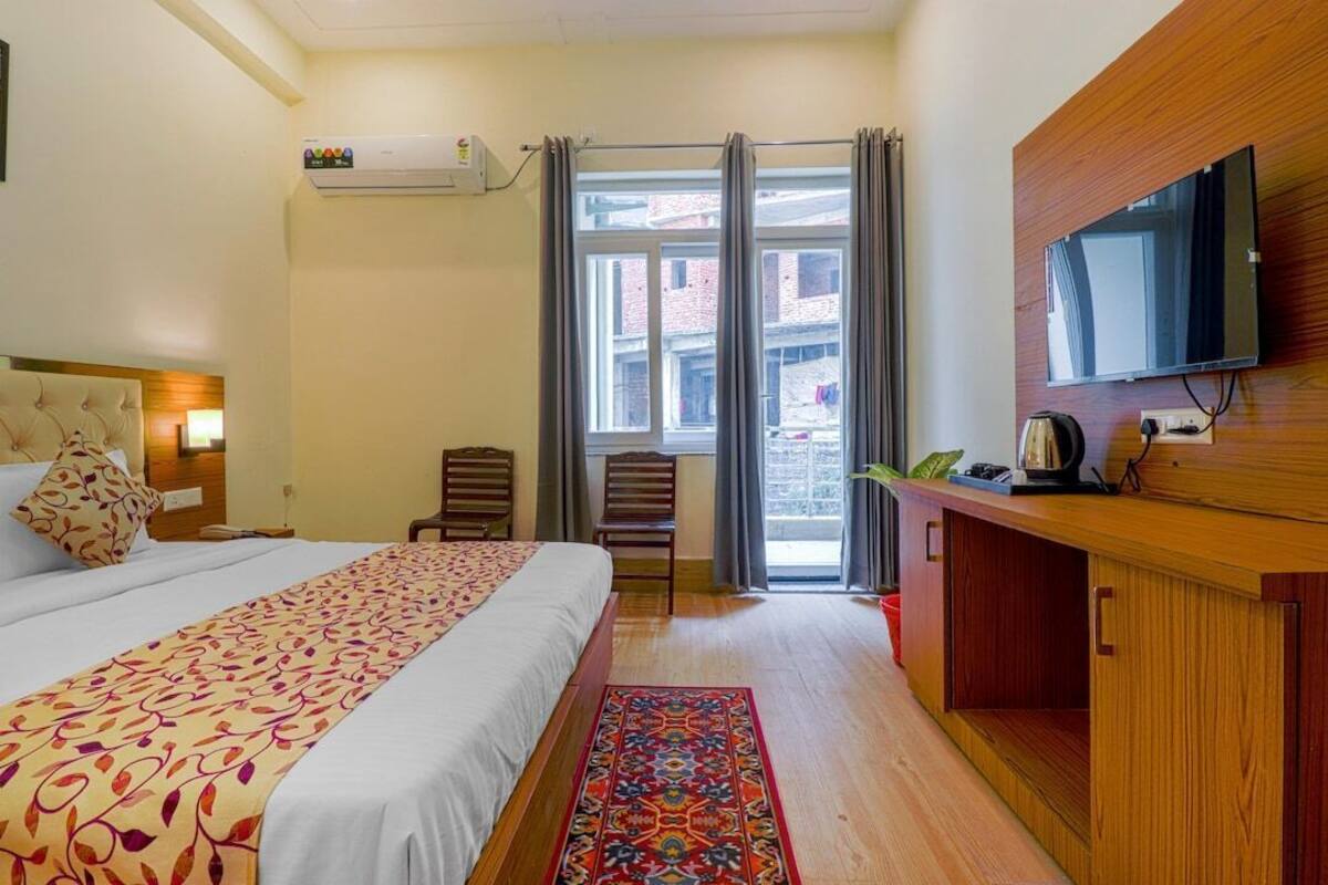 Ein Hotelzimmer mit Bett, Fernseher, Schreibtisch und einem fenster mit Vorhängen.