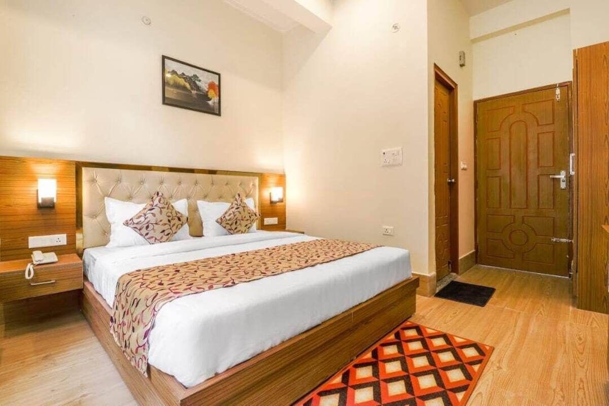 Ein Schlafzimmer mit einem großen Bett, Nachttischlampen, einem Holz-Kopfteil, einem Beistelltisch, einer Tür und einem kleinen Teppich.
