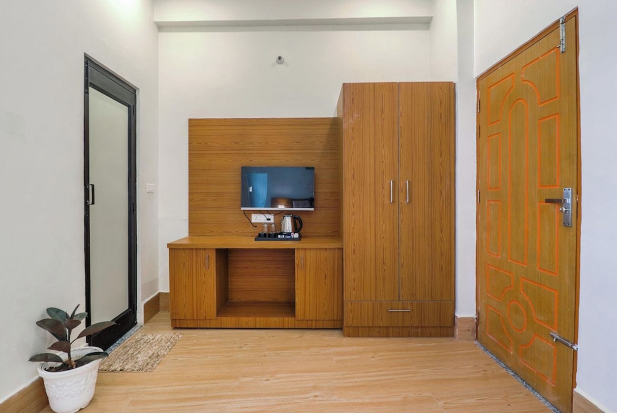 A room with a wooden cabinet, a television on a stand, and a door with a geometric design.