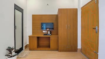 A room with a wooden cabinet, a television on a stand, and a door with a geometric design.