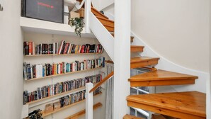 Een wenteltrap met houten treden en witte wanden, omringd door boekenkasten vol boeken.