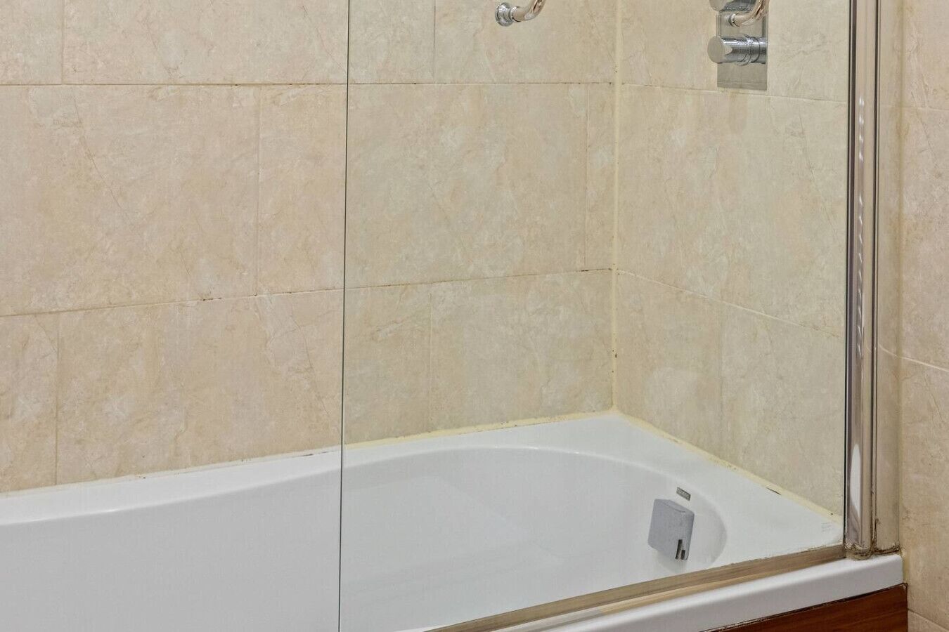 A bathroom with a bathtub, tiled walls, and a shower area.