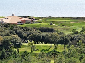 Ein Golfplatz mit Clubhaus und Meerblick.