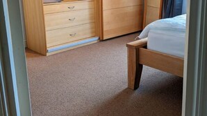 Ein Schlafzimmer mit Holzschrank, Bett und Spiegel.