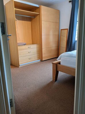A bedroom with a wooden wardrobe, a bed, and a mirror. - Spacious Double Ensuite 2 Min To Tube (Greater London)