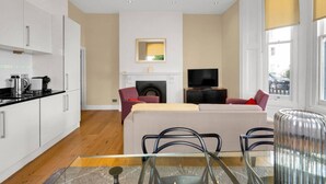 Una sala de estar moderna con sofá, televisión, chimenea y una mesa de comedor de vidrio.