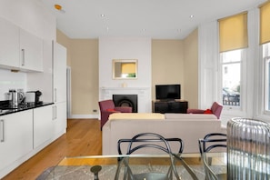 Ein modernes Wohnzimmer mit Sofa, Fernseher, Kamin und einem Glastisch.