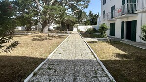 Un patio con camino de grava, árboles y un edificio con balcones.