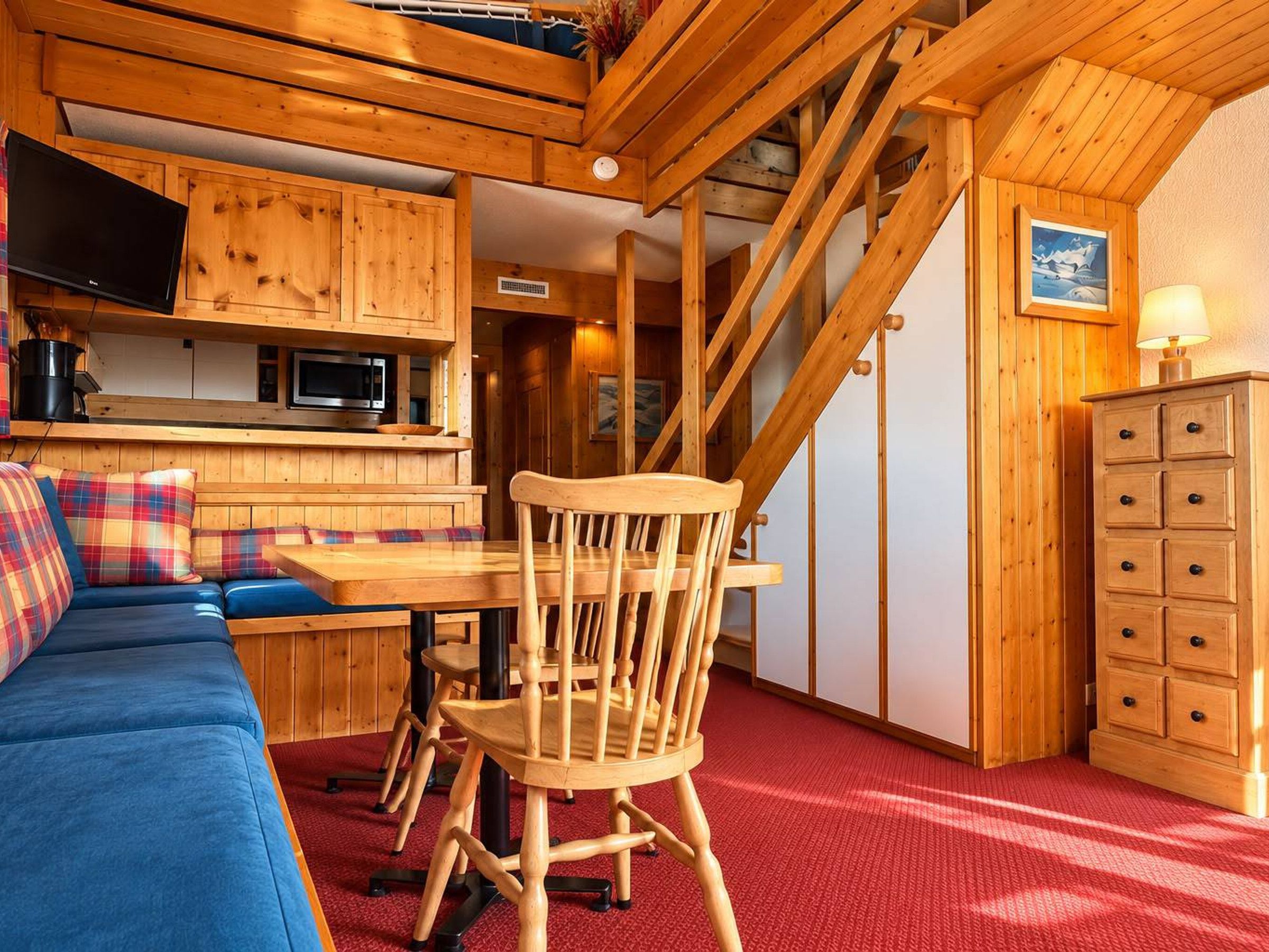 Un intérieur en bois comprenant un coin repas, un canapé et un escalier.