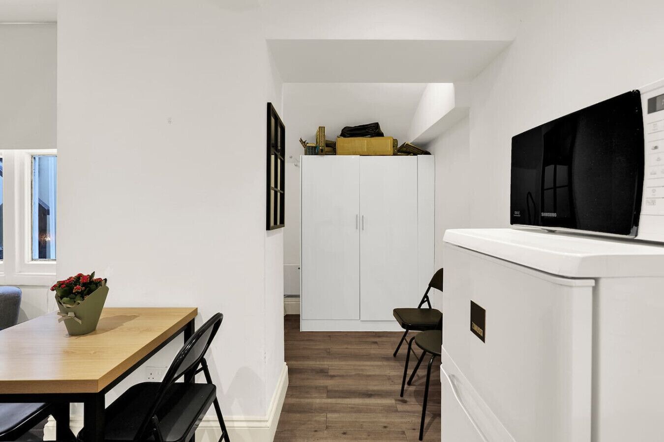 A modern kitchen with a built-in microwave, a wooden dining table, and a small seating area.