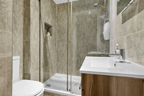 Ein modernes Badezimmer mit einer gläsernen Duschkabine, einer weißen Toilette und einem Holzlagerfläschchen mit Waschbecken.