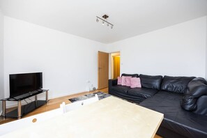 Ein modernes Wohnzimmer mit Flachbildfernseher, einer schwarzen Ledersofa und einem Holztisch.